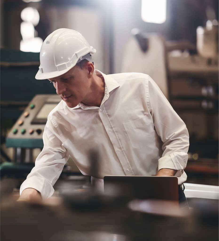 Un homme portant un casque de travail blanc vérifie de la machinerie